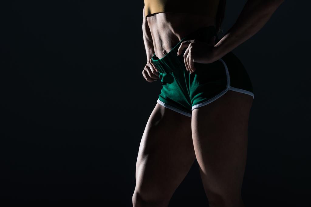 Μερική άποψη των bodybuilder με μυϊκή πόδια, απομονώνονται σε μαύρο    - Φωτογραφία, εικόνα