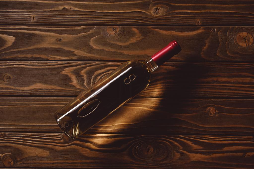 bovenaanzicht van fles witte wijn op houten tafel - Foto, afbeelding