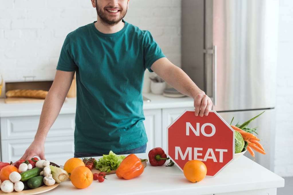 キッチンで肉記号を保持していないハンサムな菜食主義者の男の画像をトリミング - 写真・画像