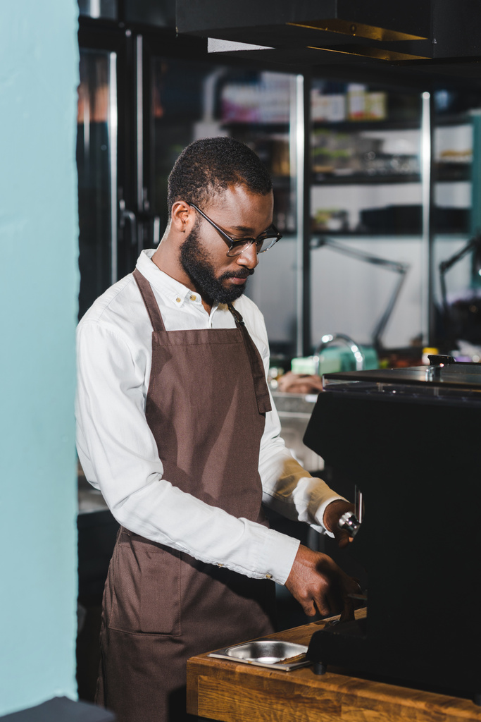pohledný mladý afroamerické barista v brýlích vaření kávy v kávovaru - Fotografie, Obrázek