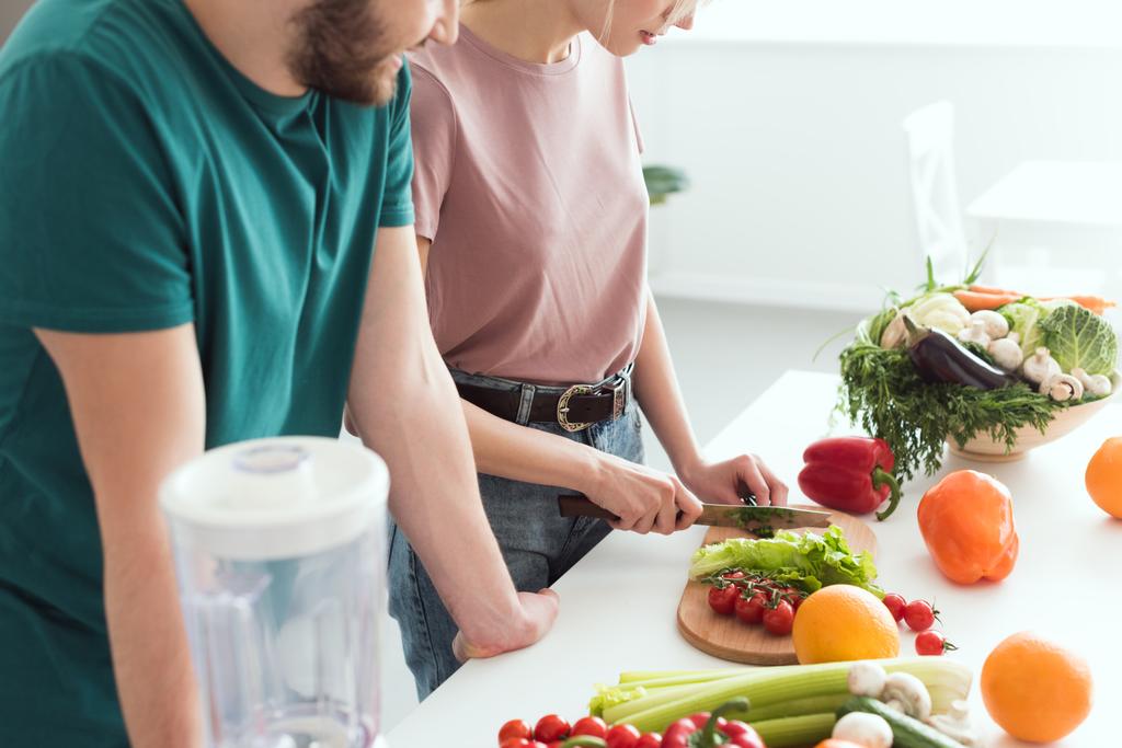 キッチンでビーガンのガール フレンド カット野菜のトリミングされた画像 - 写真・画像