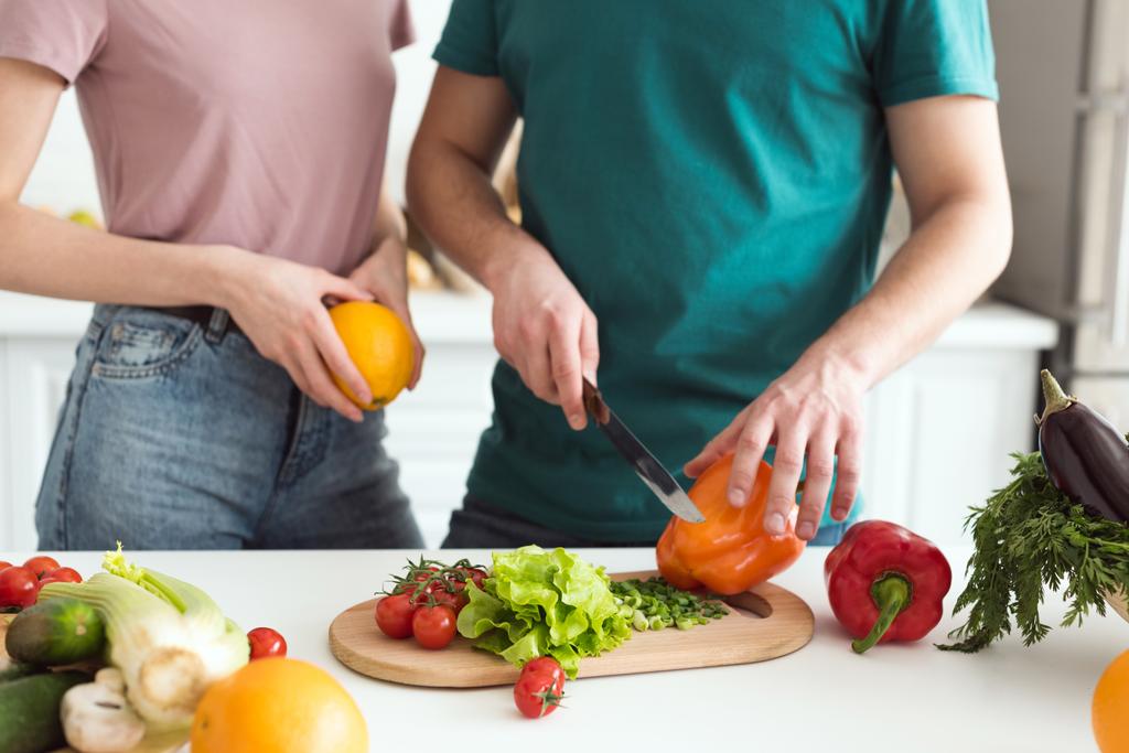 image recadrée de petit ami coupant des légumes pour salade végétarienne à la cuisine
 - Photo, image