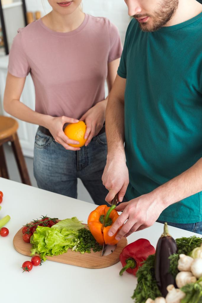 bijgesneden afbeelding van vriendje snijden groenten voor vegan salade op keuken - Foto, afbeelding