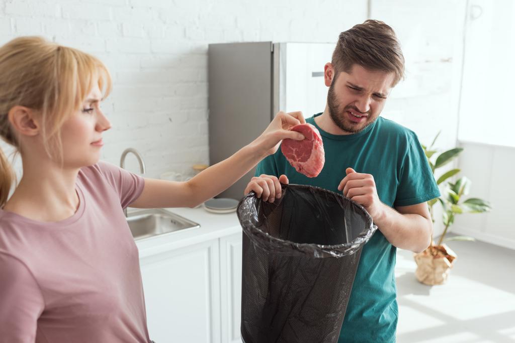 pareja tirando carne cruda en la cocina en casa, concepto de estilo de vida vegano
 - Foto, imagen