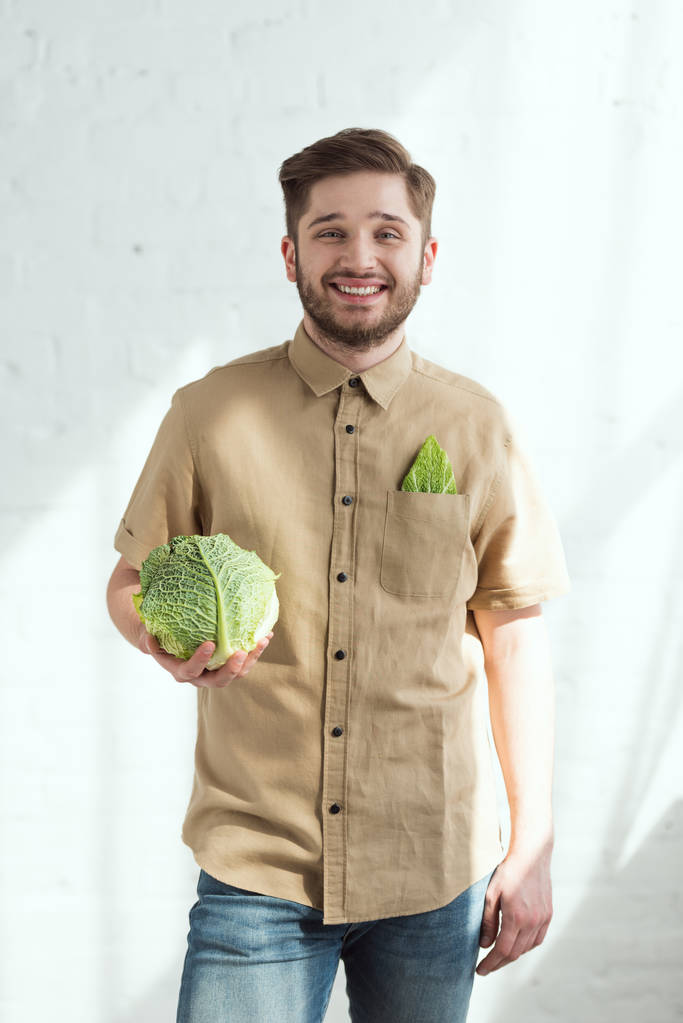 portret uśmiechający się młody człowiek ze świeżej kapusty w ręku, wegańskie lifestyle concept - Zdjęcie, obraz