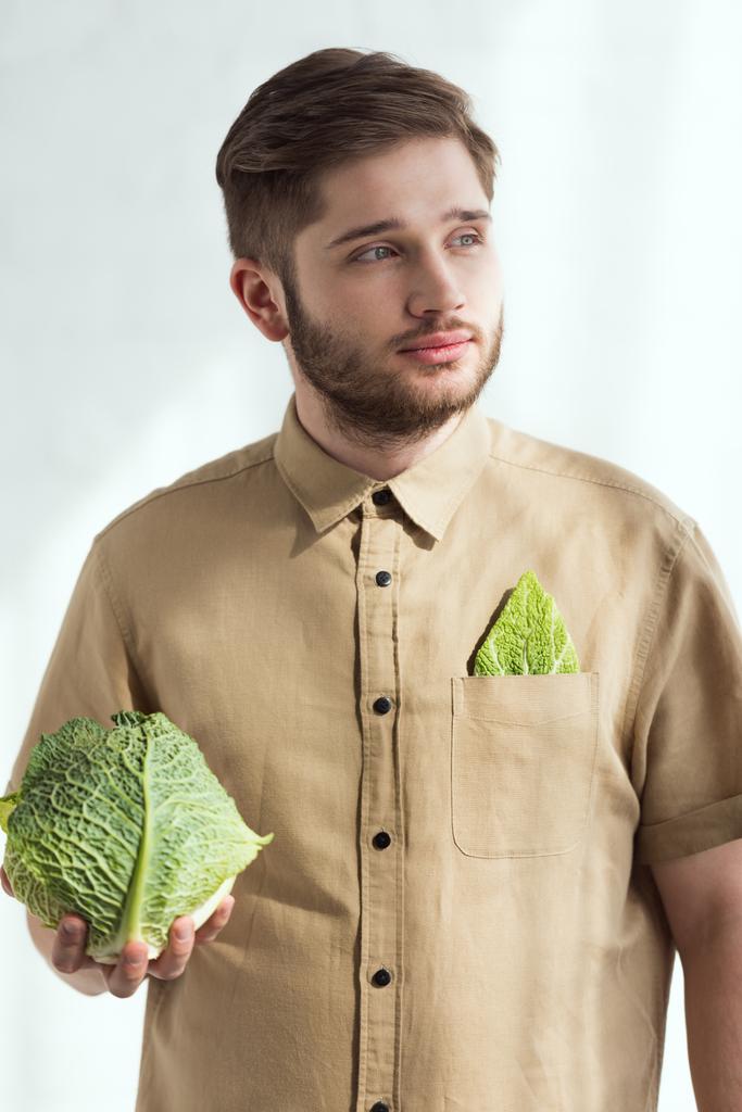retrato de un joven pensativo con col de col fresca en la mano, concepto de estilo de vida vegano
 - Foto, Imagen
