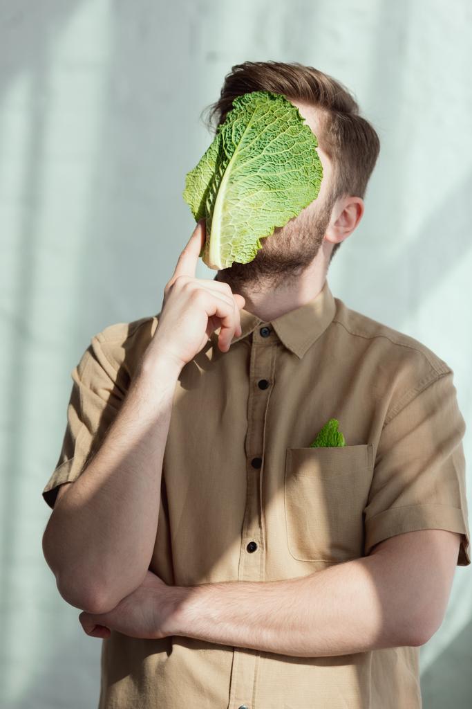 затьмарений вид на стомленого чоловіка з солоним капустяним листом на обличчі, концепція веганського способу життя
 - Фото, зображення