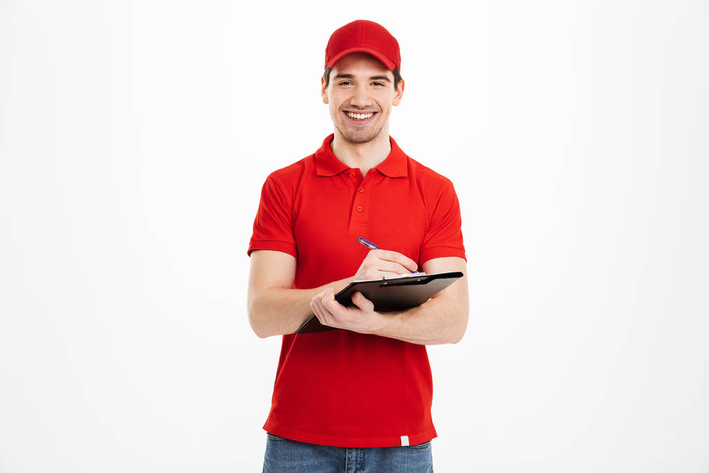 Portrait of smiling delivery man in red t-shirt and cap looking  - Photo, Image