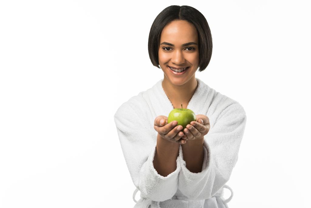 χαμογελώντας αφρικανικό αμερικανικό κορίτσι με Οδοντική Τιράντες κρατώντας μήλο, απομονώνονται σε λευκό - Φωτογραφία, εικόνα