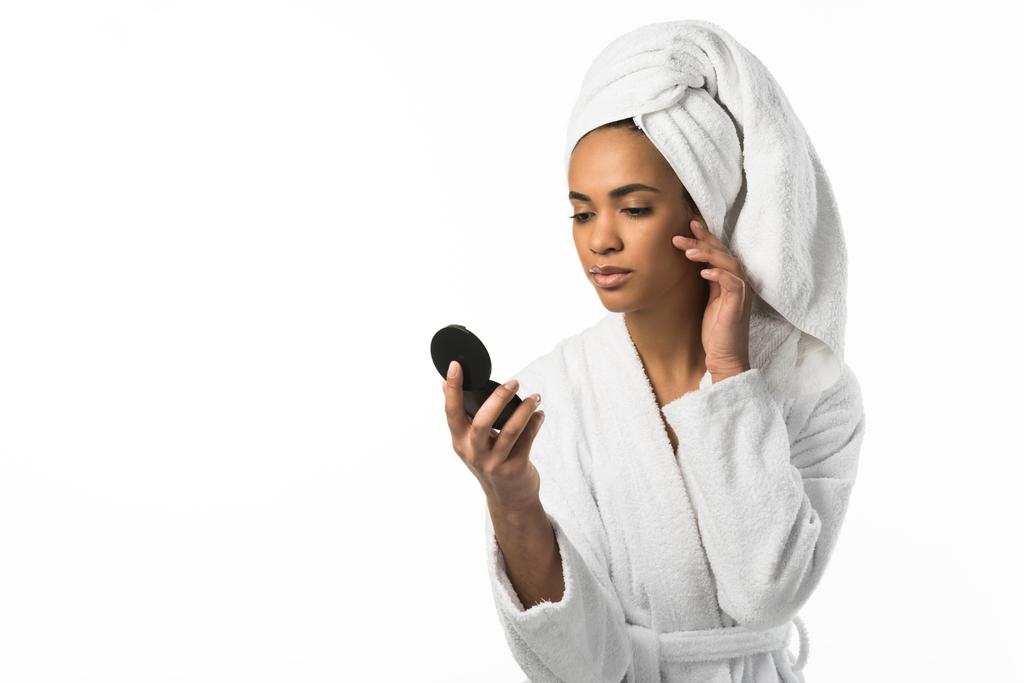 mujer afroamericana en albornoz y toalla mirando al espejo, aislada en blanco
 - Foto, imagen