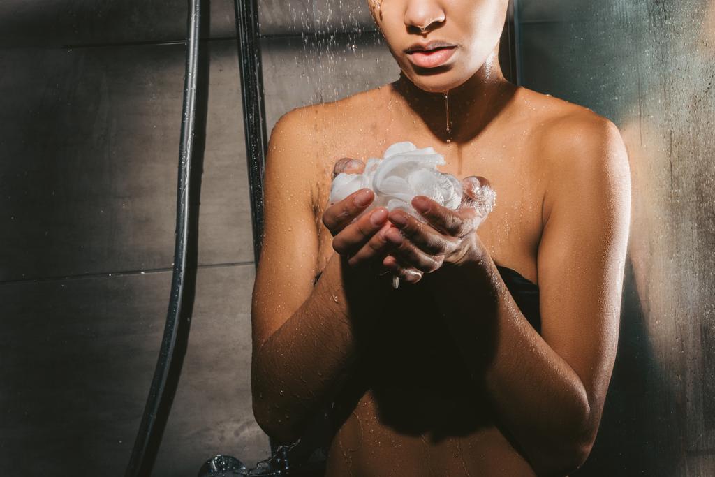 Afrikalı-Amerikalı kadın köpük ve sünger ile duş alırken kırpılmış görünümü - Fotoğraf, Görsel