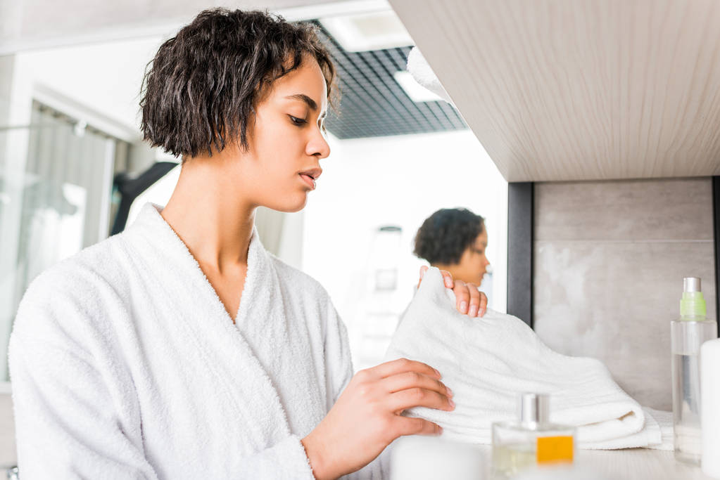prachtige Afrikaanse Amerikaans meisje in badjas nemen handdoek in de badkamer - Foto, afbeelding