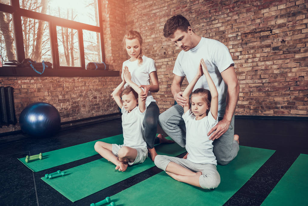 Vader en moeder helpen kinderen beoefenen van yoga in sportschool - Foto, afbeelding