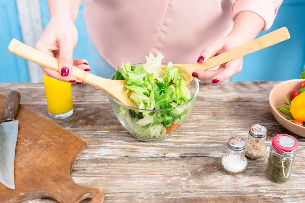 обрезанный снимок женщины с избыточным весом, готовящей свежий салат на ужин дома на кухне
 - Фото, изображение