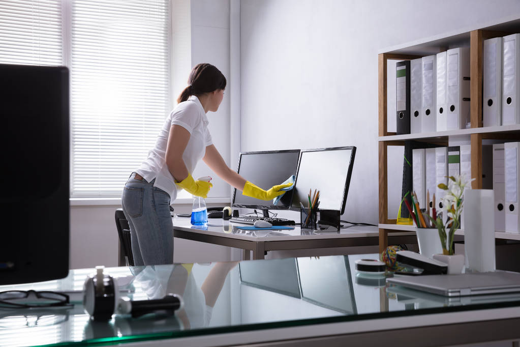 junge Frau putzt Computer mit Lappen im Büro - Foto, Bild