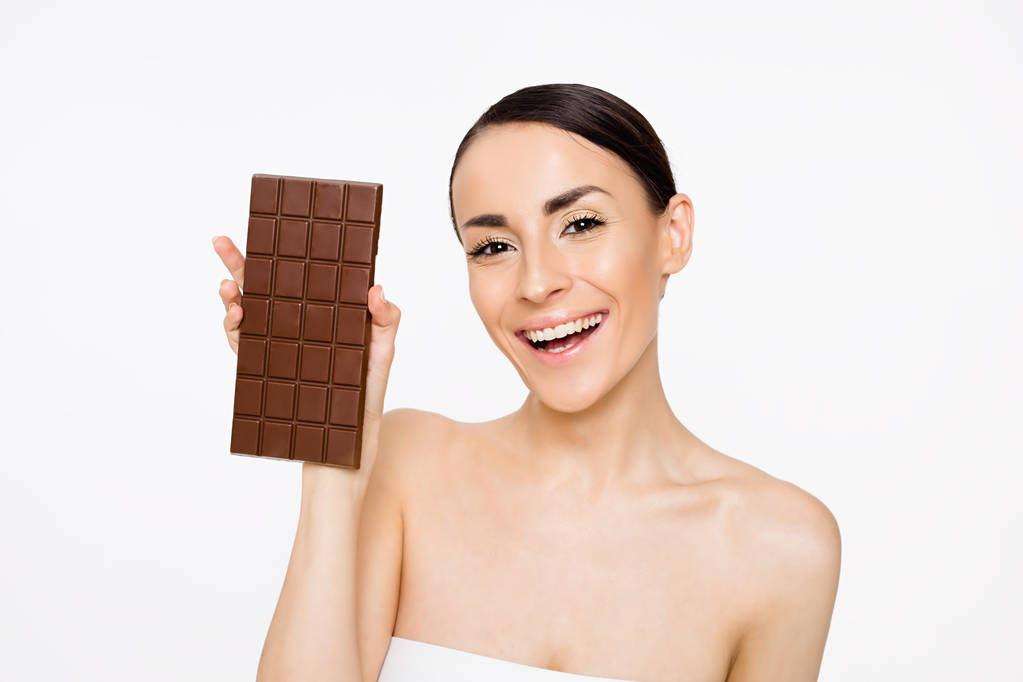 natürliche Schokolade. schöne, fröhliche junge Frau hält eine Kachel schwarze Schokolade in den Händen auf weißem Hintergrund - Foto, Bild