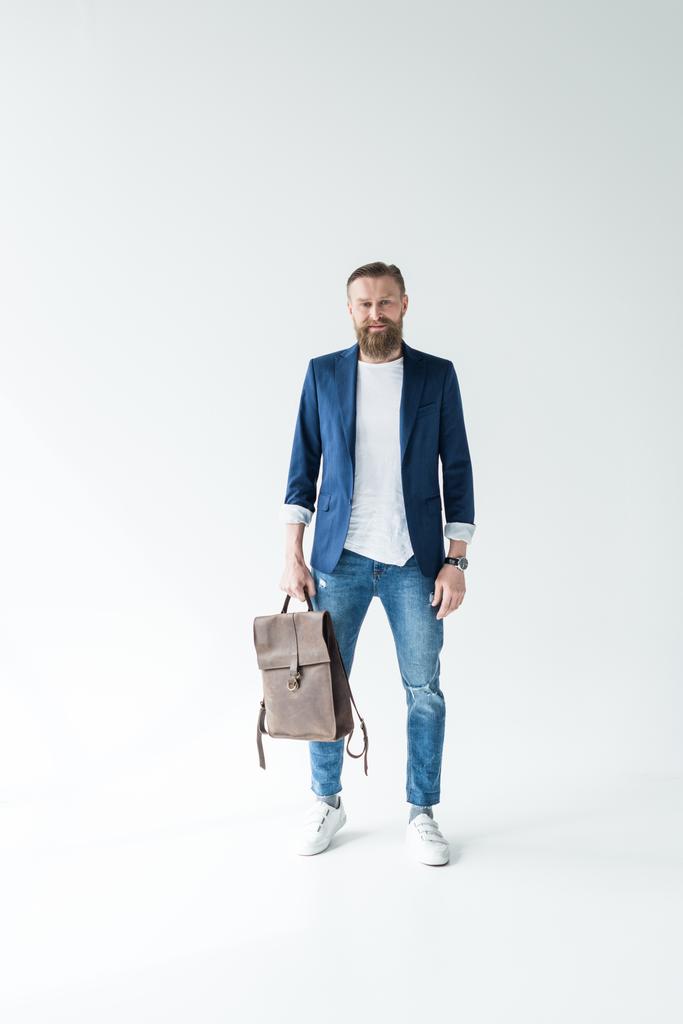 Стильний бородатий чоловік тримає рюкзак на світлому фоні
 - Фото, зображення