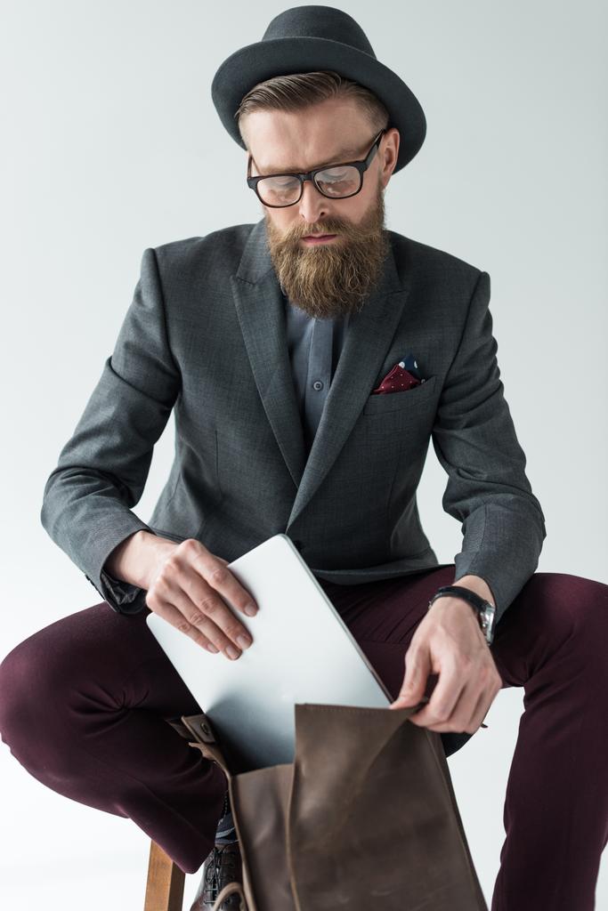 Bonito homem de negócios em roupas de estilo vintage com laptop e mochila isolada no fundo claro
 - Foto, Imagem