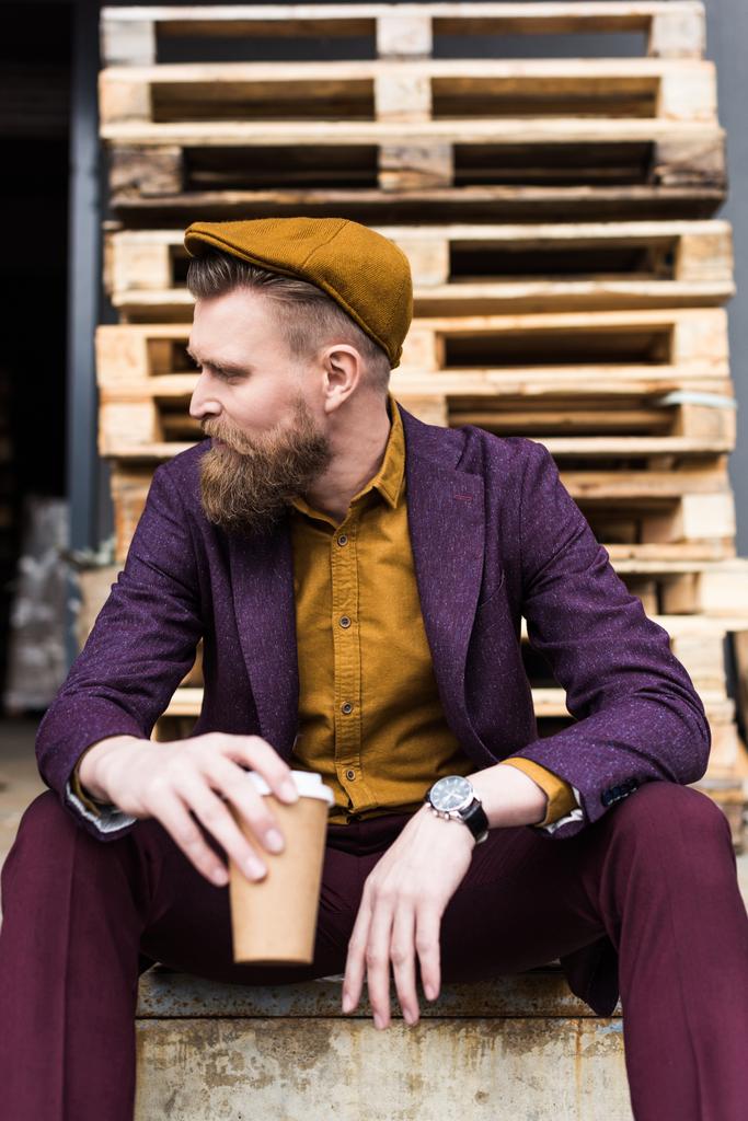 Biznesmen z rocznika wąsy i brodę, siedząc na ulicy z papieru Puchar w ręce - Zdjęcie, obraz