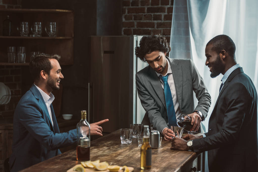 pohledný mladý mužský přátel pití alkoholických nápojů a mluví při párty společně  - Fotografie, Obrázek