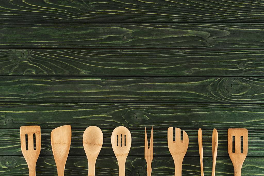 top view of kitchen utensils placed in row on rustic wooden table - Photo, Image