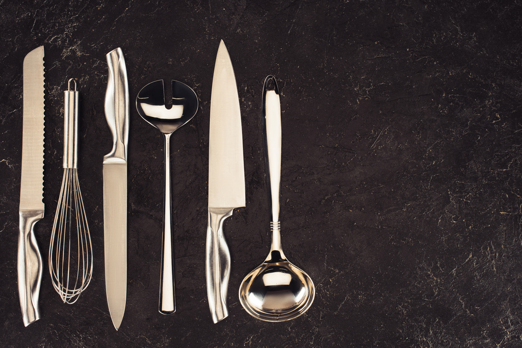 vista elevada de los utensilios de cocina colocados en fila sobre la mesa de mármol negro
 - Foto, imagen