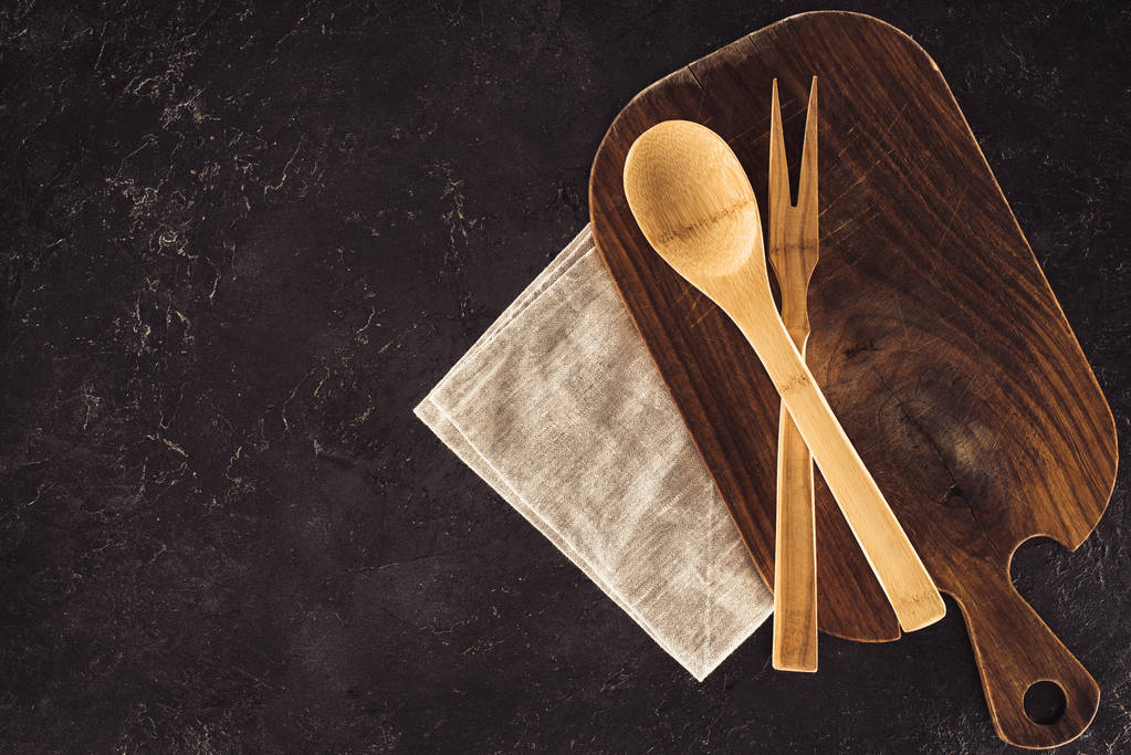 bovenaanzicht van lepel, vork voor vlees op houten snijplank en zak - Foto, afbeelding