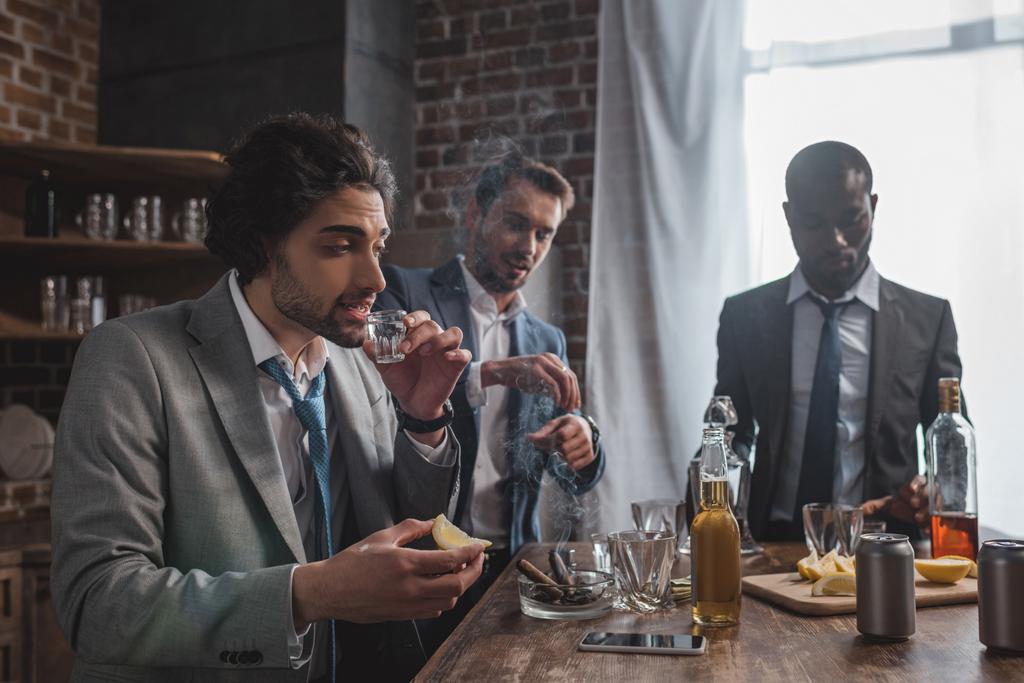 багатоетнічні друзі чоловічої статі в формальному носінні пити текілу і курити сигари
 - Фото, зображення