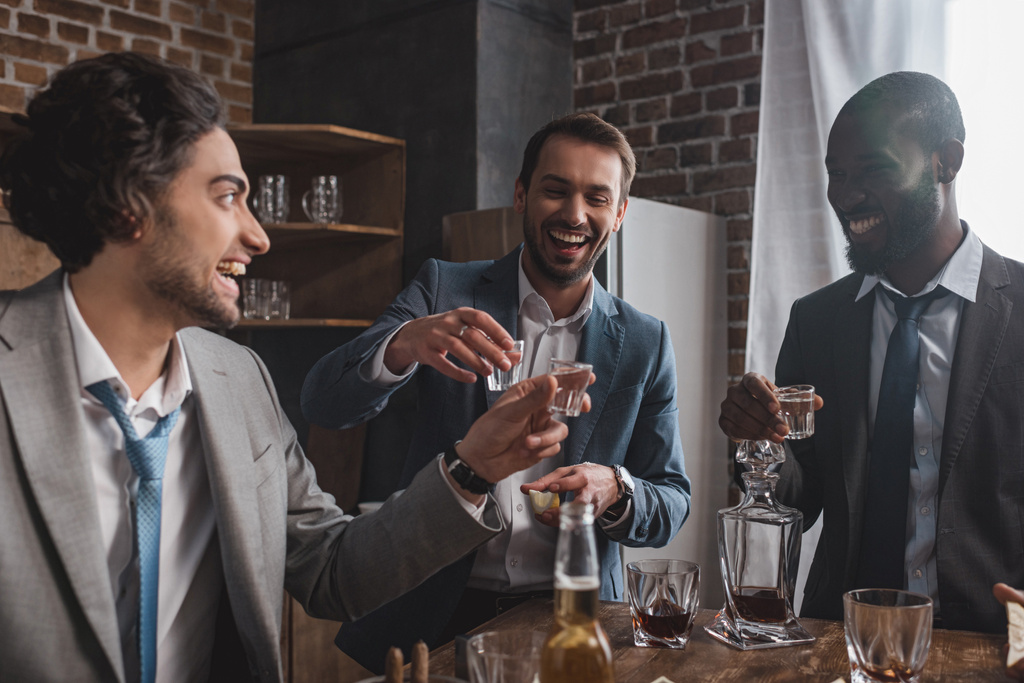 hymyilevä monikansallinen mies ystäviä puvuissa juominen tequila yhdessä
  - Valokuva, kuva