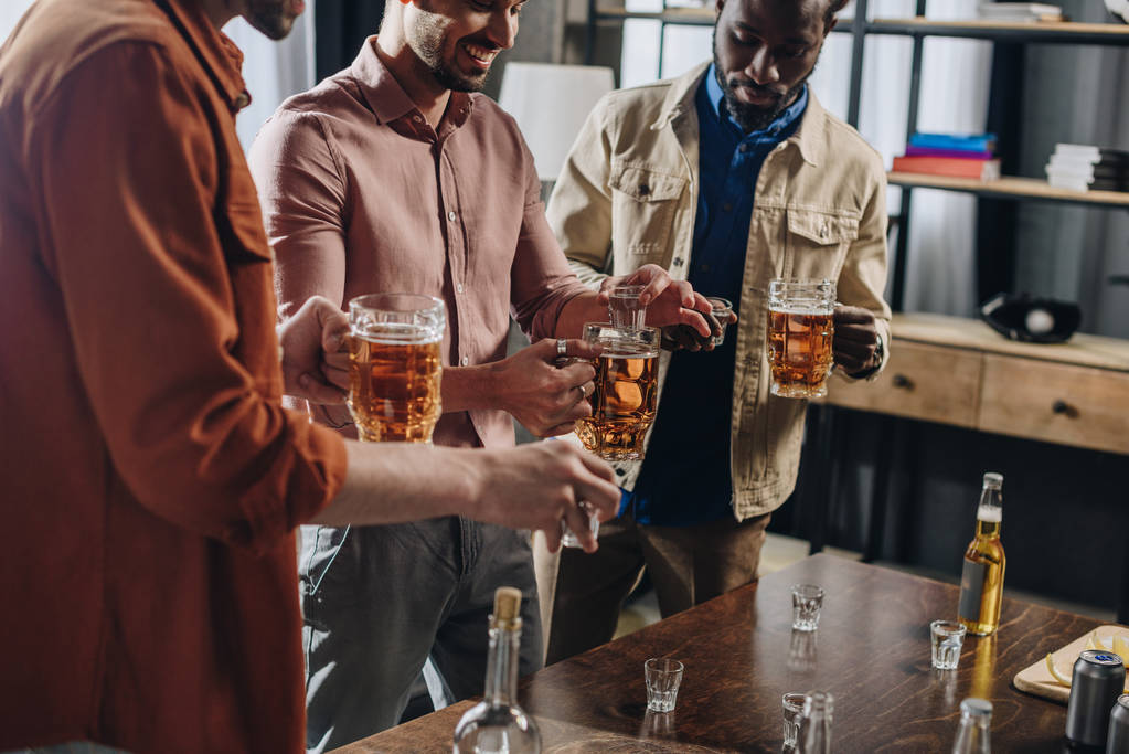 обрезанный снимок улыбающихся мультиэтнических мужчин, пьющих алкогольные напитки вместе
 - Фото, изображение