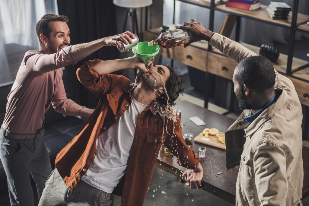 hoge hoekmening van man uit trechter terwijl vrienden gieten van alcoholische dranken drinken  - Foto, afbeelding