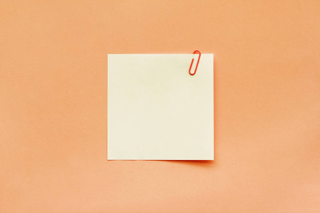 Etiqueta de papel blanco con clip sobre fondo naranja
 - Foto, Imagen