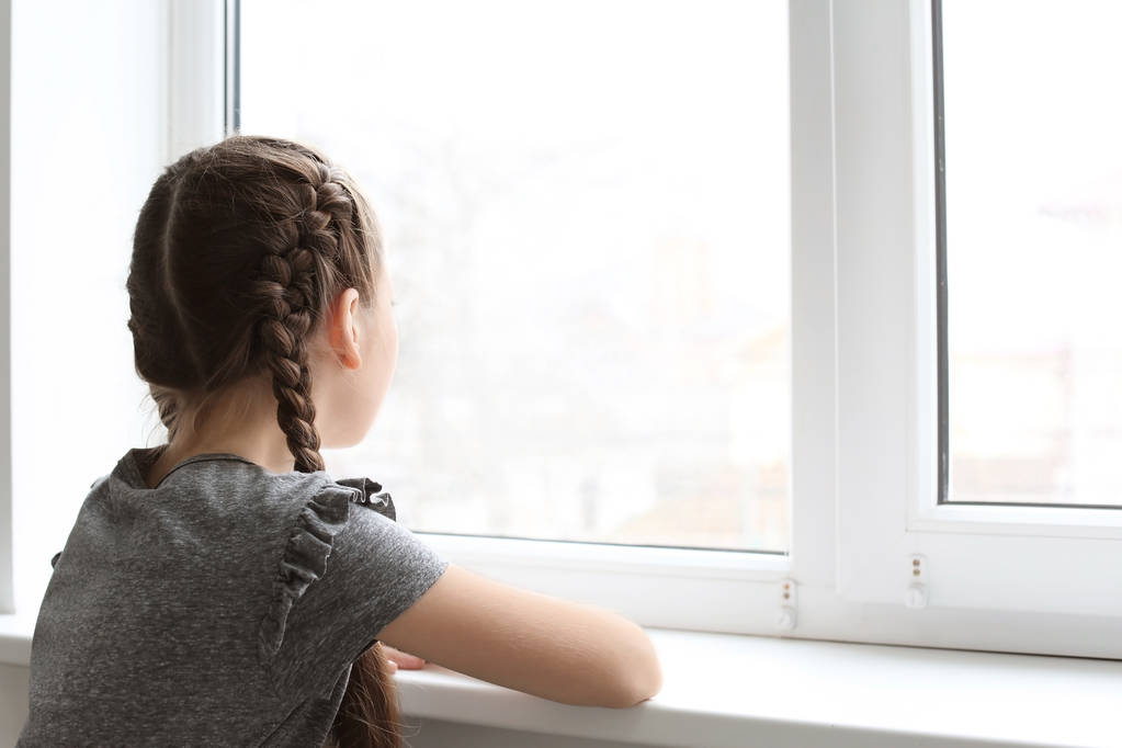Samotna dziewczynka w pobliżu okna w pomieszczeniu. Autyzm dziecko - Zdjęcie, obraz
