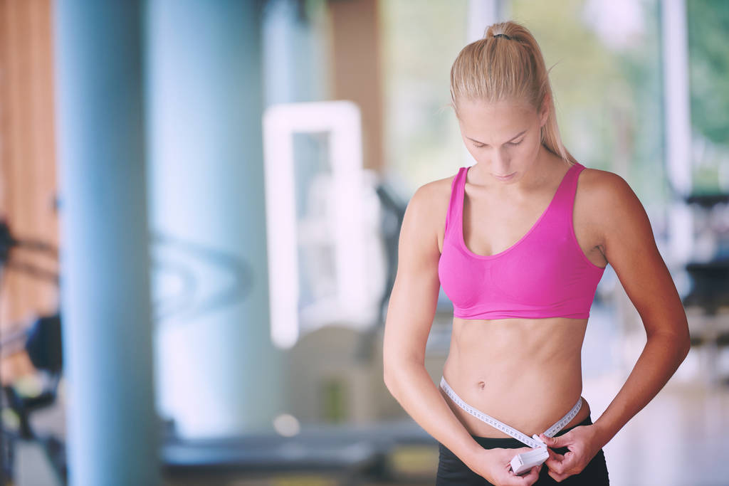 młoda kobieta fit pomiaru brzucha na treningu w siłowni - Zdjęcie, obraz