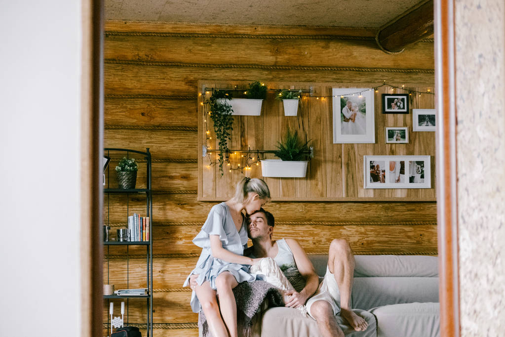 Krásný pár spolu doma. Krásná žena a atraktivní muž stylové ležérní oblečení sedí na pohovce objímání a líbání - Fotografie, Obrázek