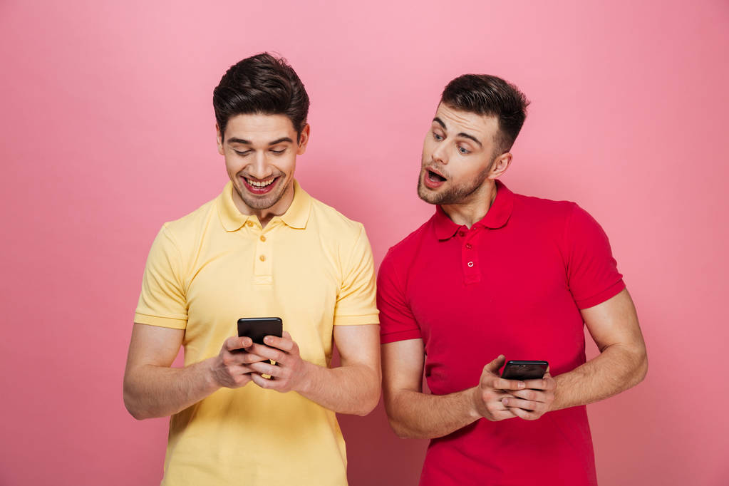 Πορτρέτο του ένα χαρούμενο γκέι ζευγάρι χρησιμοποιώντας τα κινητά τηλέφωνα - Φωτογραφία, εικόνα