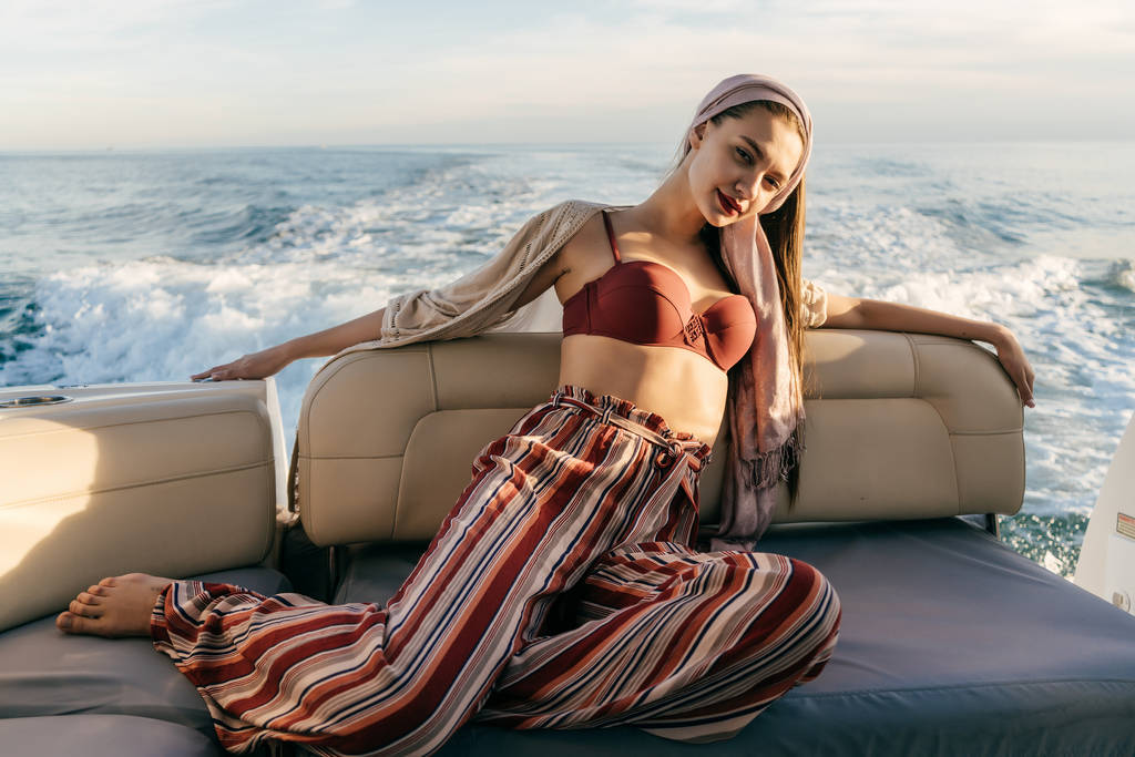 una ragazza ricca in eleganti abiti estivi siede sul suo yacht bianco, gode di una vacanza e un viaggio al mare
 - Foto, immagini