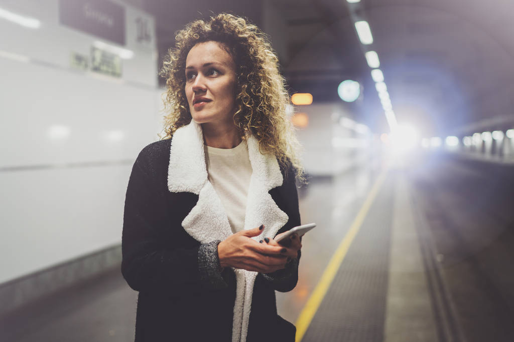 駅で立っている間スマート フォンを使用しての通勤輸送のきれいな女性。幸せな休暇旅行での会話、携帯電話アプリを使用して魅力的な女の子. - 写真・画像