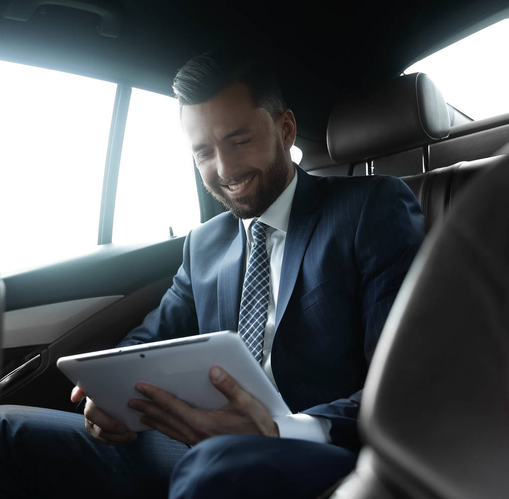 hombre de negocios con una tableta digital sentado en el asiento trasero de un coche
 - Foto, Imagen