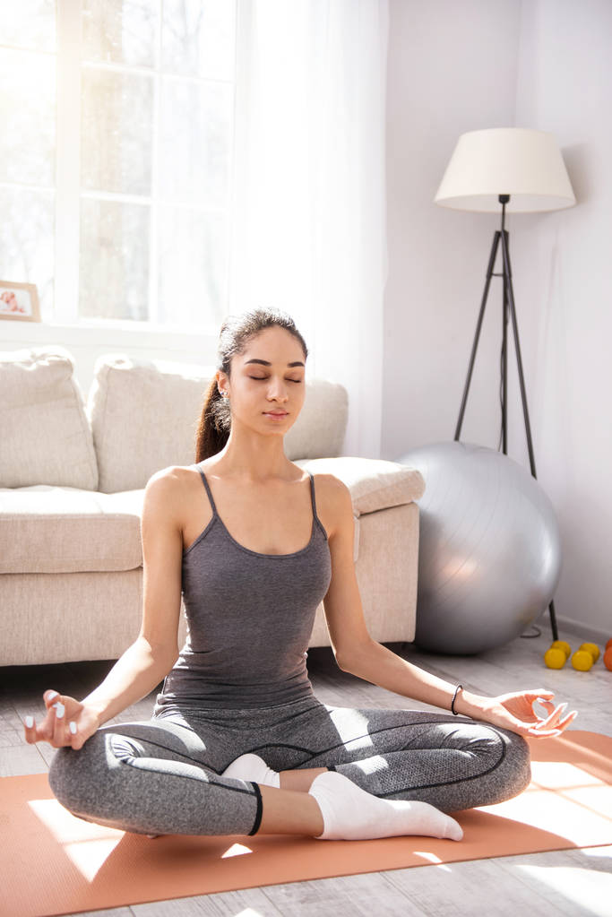 Charmante junge Frau praktiziert Yoga zu Hause - Foto, Bild