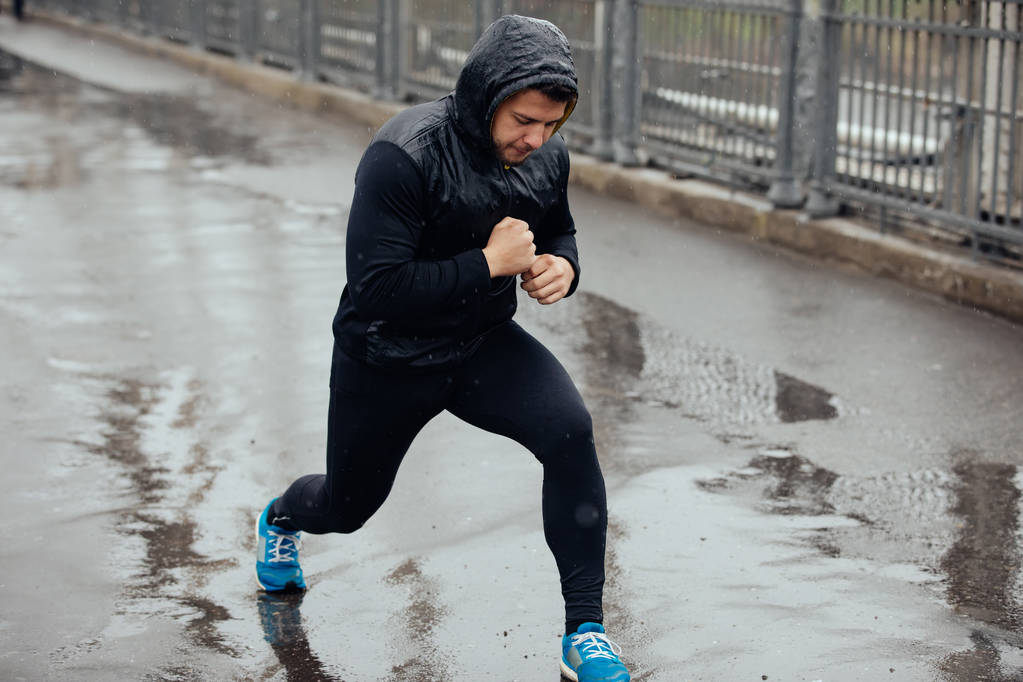 Sport uomo jogger riscaldamento sul ponte in giorno di pioggia
 - Foto, immagini