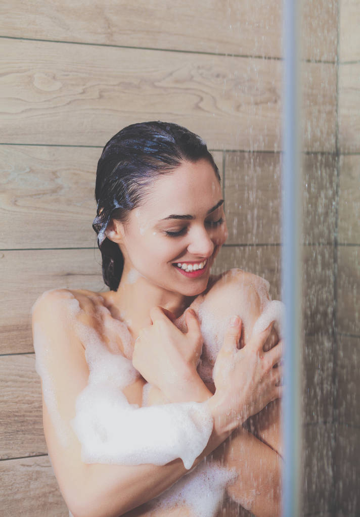 Jovem mulher bonita sob o chuveiro no banheiro
. - Foto, Imagem