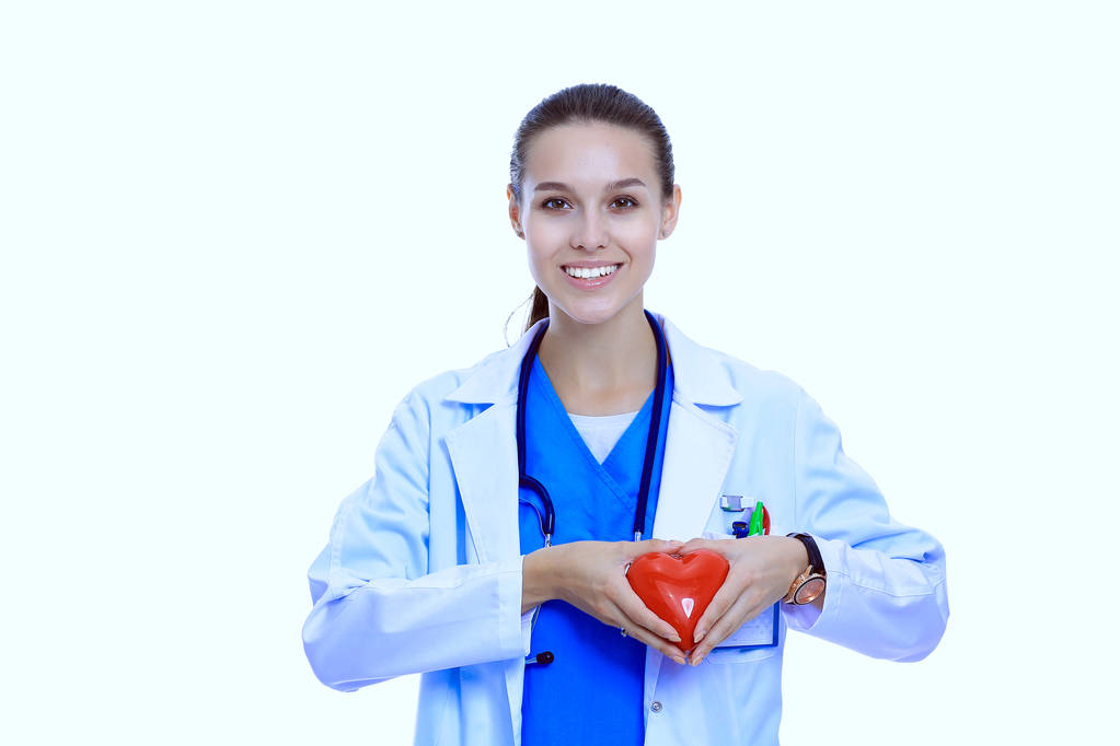 Positive female doctor standing with stethoscope and red heart symbol isolated. Woman doctor - Photo, Image