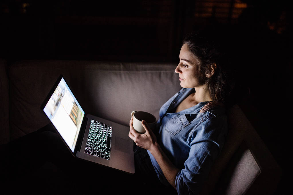 Una mujer que trabaja en un portátil por la noche
. - Foto, Imagen