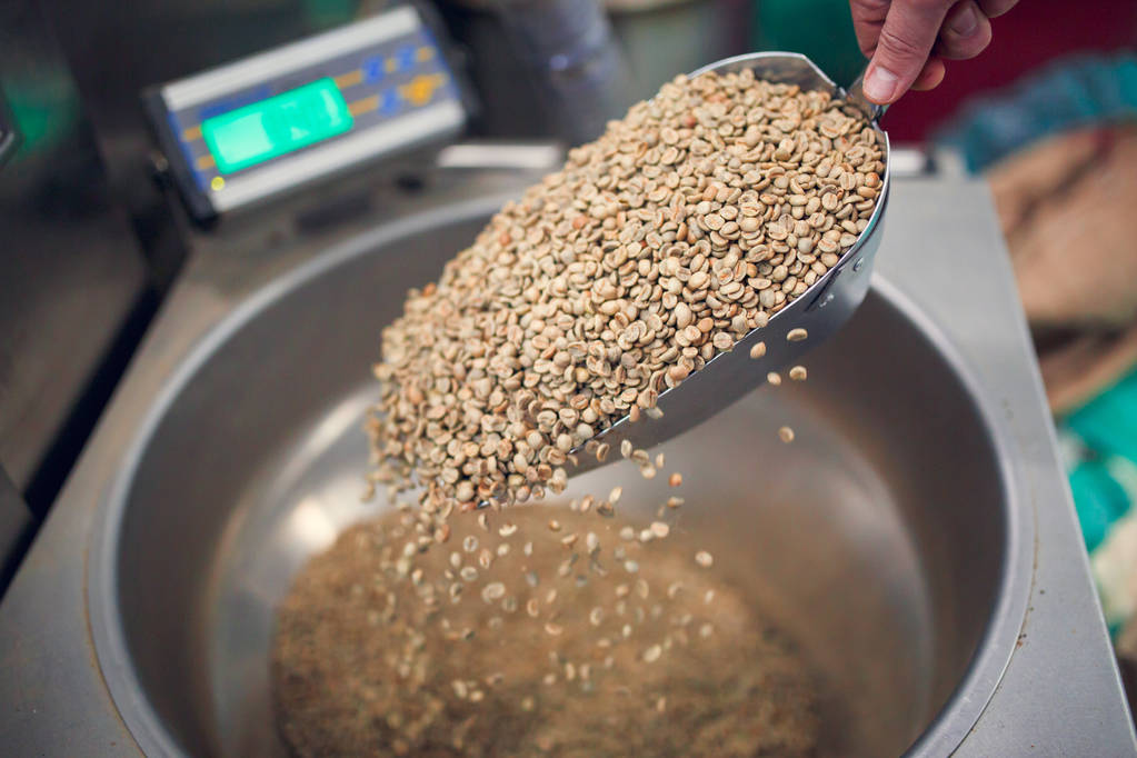 Image of mans hand with scoop with spilling grains of coffee, industrial scales - Photo, Image