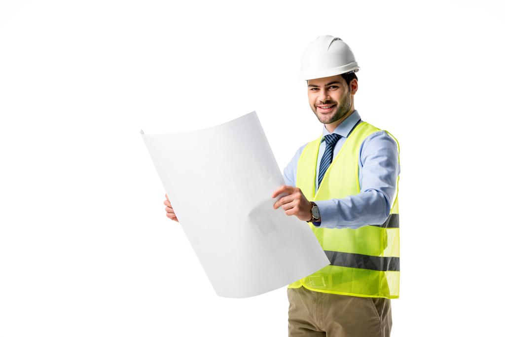 Smiling builder in reflective vest and hardhat looking at blueprint isolated on white - Photo, Image