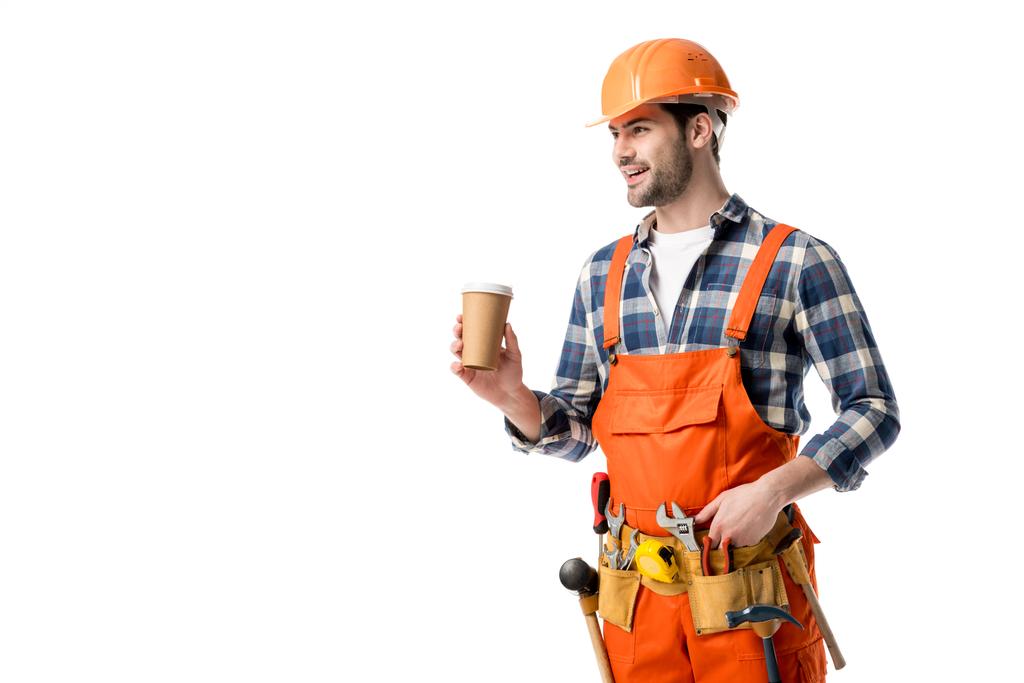 Construtor sorridente em laranja geral e cinto de ferramentas beber café isolado em branco
 - Foto, Imagem