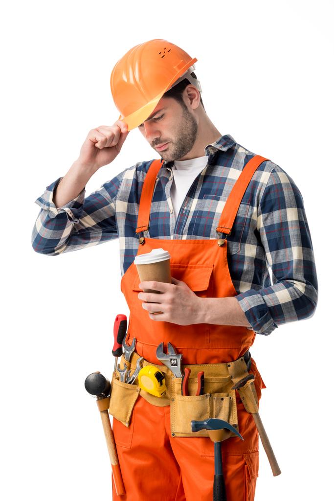 Reparador em laranja geral e capacete segurando xícara de café isolado no branco
 - Foto, Imagem