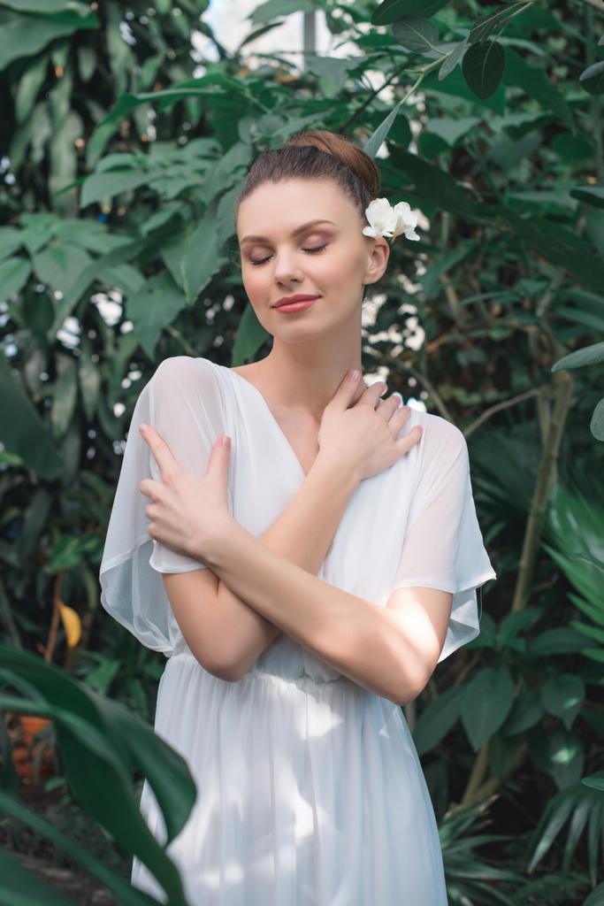 bella sposa in abito bianco con gli occhi chiusi in posa nel giardino tropicale
 - Foto, immagini