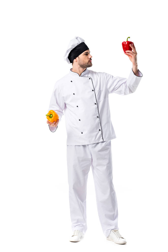joven chef en uniforme con pimientos frescos en manos aisladas en blanco
 - Foto, Imagen